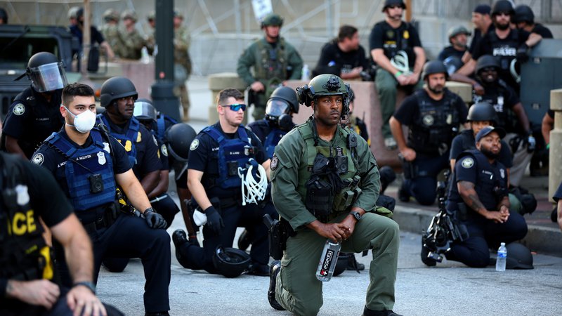 Fotografija: Med protesti v centru Atlante v ameriški zvezni državi Georgia so se tudi nekateri policisti skupaj s protestniki poklonili umrlemu temnopoltemu Georgeu Floydiu tako da so počepnili. FOTO: Dustin Chambers/Reuters