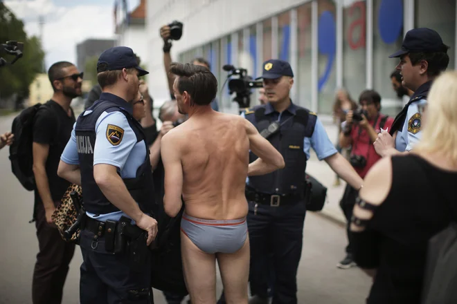 Akcija je potekala utečeno in mirno, dokler igralec Primož Bezjak ni slekel svoje obleke in jo z lepilnim trakom prilepil na steklena vrata, takrat so policisti skočili, ga obstopili in zahtevali osebne dokumente. Foto: Jure Eržen