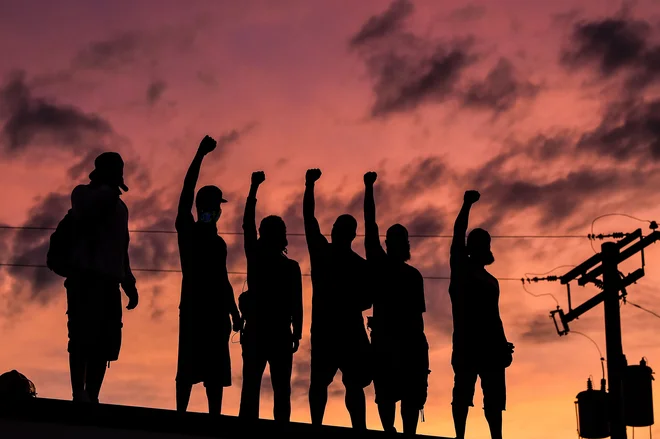 TOPSHOT - People raise their hands and shout slogans as they protest at the makeshift memorial in honour of George Floyd, on June 2, 2020 in Minneapolis, Minnesota. - Thousands of National Guard troops patrolled major US cities after protests over racism and police brutality boiled over into arson and looting, sending shock waves through the country. (Photo by CHANDAN KHANNA / AFP)