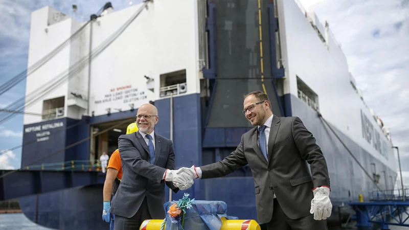 Fotografija: Minister Jernej Vrtovec in predsednik uprave Dimitrij Zadel sta simbolično privezala ladjo Neptun Kefalonia, ki bi lahko pripeljala skoraj 3000 avtomobilov, a jih je v Koper tokrat precej manj. FOTO: Blaž Samec/Delo