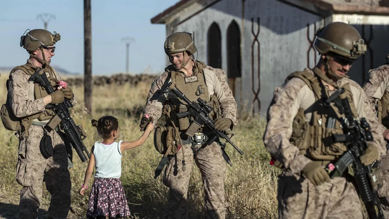 Fotografija: Sirska deklica ameriškim vojakom deli cvetje, medtem ko se je njihov konvoj ustavil na podeželju severovzhodnega sirskega mesta Al Malikiyah (Derik) ob meji s Turčijo. FOTO: Delil Souleiman/AFP