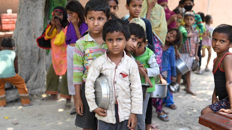 Fotografija: Indijski otroci iz revnega predela New Delhija čakajo v vrsti za brezplačno hrano. FOTO: Prakash Singh/Afp
 