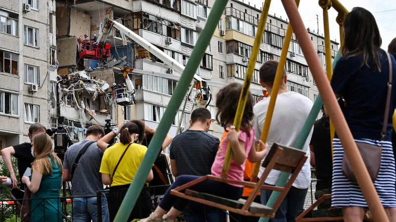 Fotografija: Lokalni prebivalci Kijeva opazujejo reševalce, kako odstranjujejo ruševine v stanovanjskem naselju, kjer je prišlo do plinske eksplozije. Ena oseba je umrla, uničenih je več stanovanj. FOTO: Genya Savilov/Afp