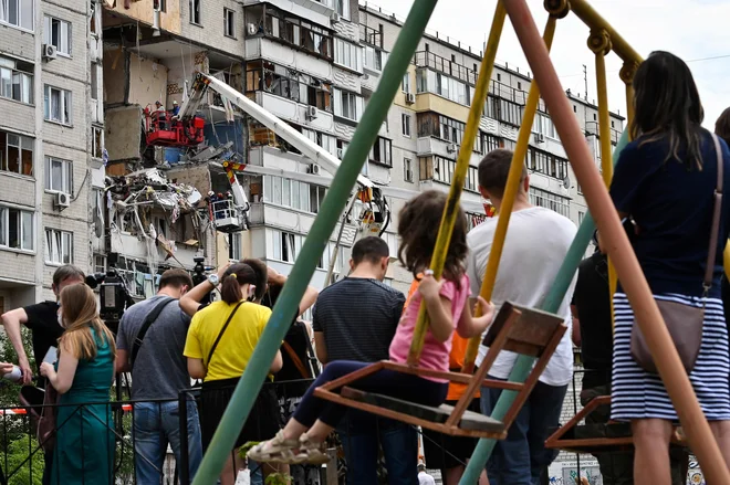 Lokalni prebivalci Kijeva opazujejo reševalce, kako odstranjujejo ruševine v stanovanjskem naselju, kjer je prišlo do plinske eksplozije. Ena oseba je umrla, uničenih je več stanovanj. FOTO: Genya Savilov/Afp<br />
&nbsp;