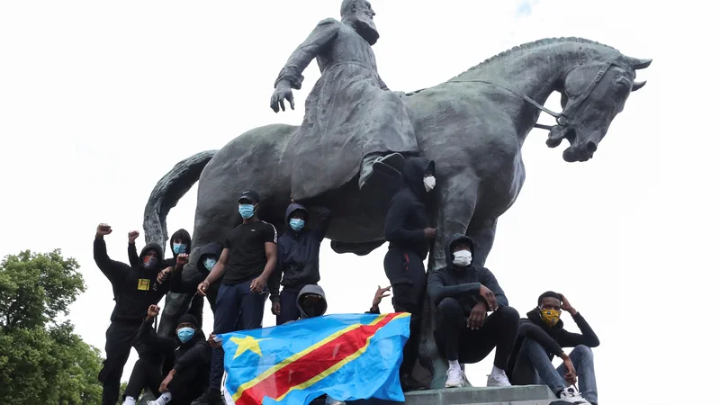 Fotografija: Protestniki na spomeniku kralju Leopoldu II. pri kraljevi palači središču Bruslju. FOTO: Yves Herman/Reuters