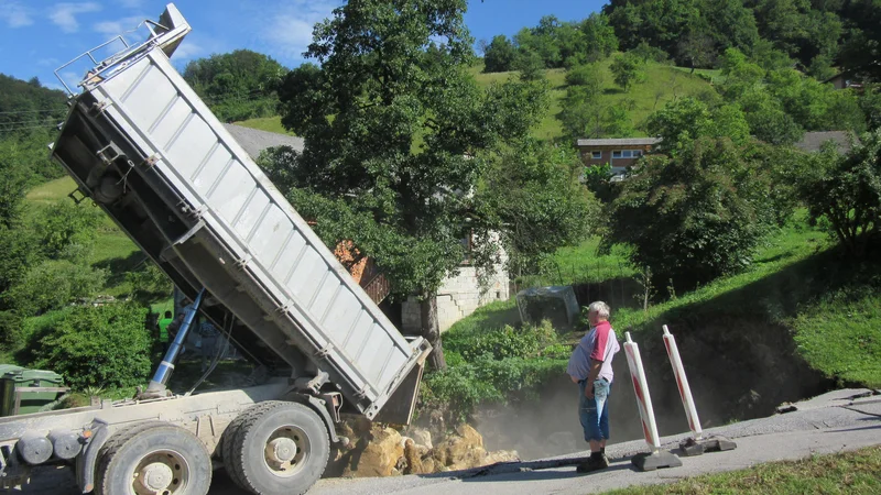 Fotografija: Dopoldne so veliko jamo, ki je nastala zaradi udora zemlje, začeli polniti s skalami. FOTO: Špela Kuralt/Delo