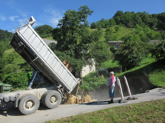 Dopoldne so veliko jamo, ki je nastala zaradi udora zemlje, začeli polniti s skalami. FOTO: Špela Kuralt/Delo