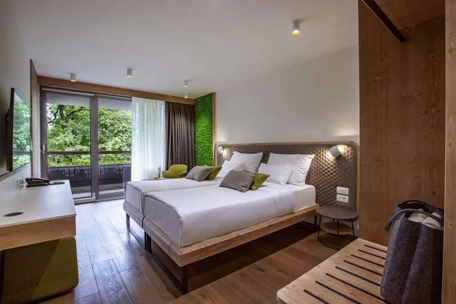Sobe, ki pripovedujejo zgodbo gozda, so pomirjujoče zelene, podobe gozda in dreves nas pozdravljajo s stenskih poslikav, pogled skozi okno pa se zazre v zeleno. FOTO: Sava Hotels & Resorts