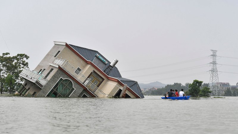 Fotografija: Kitajci se vozijo s čolnom mimo uničene hiše, ki je bila prizadeta zaradi poplav v bližini jezera Poyang v osrednji kitajski provinci Jiangxi. Kitajsko je prizadelo obilno deževje, ki je povzročilo tudi obsežne poplave. Sprožili so se tudi številni zemeljski plazovi. Več milijonov ljudi je moralo zapustiti svoje domove. Številni so pogrešani, našteli so že tudi najmanj 141 mrtvih. FOTO: Stringer/Afp
 
