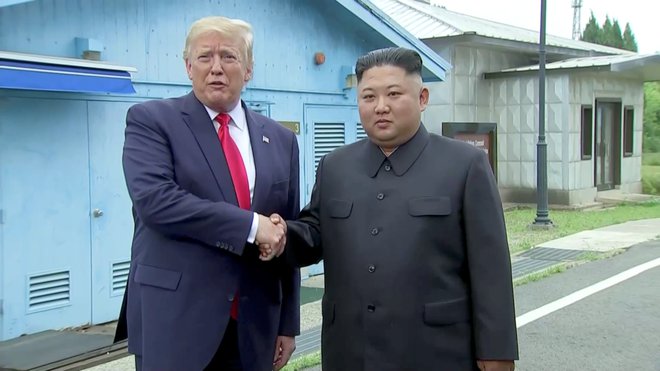 Donald Trump in Kim Džong Un sta si segla v roke. FOTO: Reuters