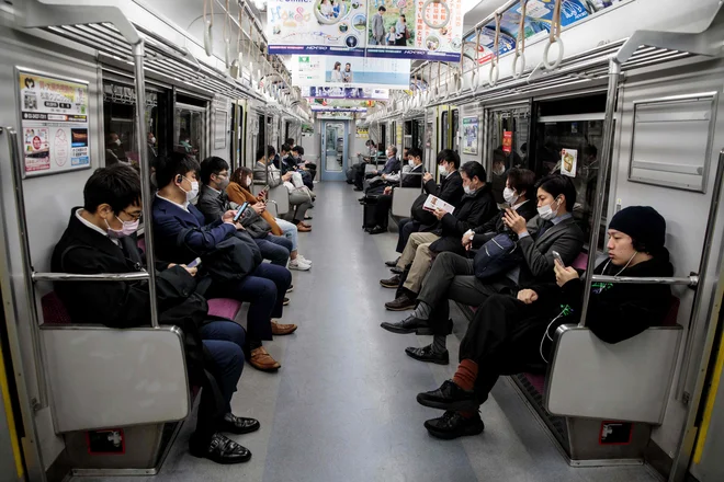TOPSHOT - People wearing face masks amid concerns over the spread of the COVID-19 coronavirus, commute on a train in Tokyo on April 6, 2020. (Photo by Behrouz MEHRI / AFP) Foto Behrouz Mehri Afp