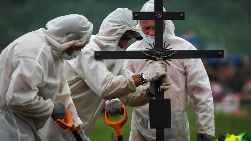 Fotografija: Matematik Mihail Tamm, docent na moskovski državni univerzi, se že od izbruha epidemije redno ukvarja z analizami uradnih statistik. Po njegovem je pravo število mrtvih vsaj za 60 odstotkov večje od uradno objavljenih podatkov. Na fotografiji: pogreb blizu Sankt Peterburga FOTO: Anton Vaganov/Reuters