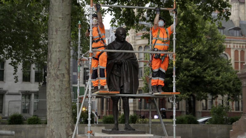 Fotografija: Potem ko so v Amsterdamu kip Gandhija premazali z barvo in popisali z grafiti, so oblasti v Londonu kip indijskega politika in aktivista iz previdnosti zaščitile. Foto Matt Dunham/AP