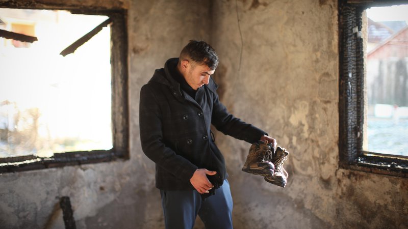 Fotografija: Alžirec Abdul Mamun v svoji sobi, ki je pred kratkim pogorela. Edino, kar je 22-letniku ostalo, so pohodni čevlji. Možnosti, da ga bodo ponesli v obljubljeno deželo Evropo, je vse manj. FOTO: Jure Eržen/Delo