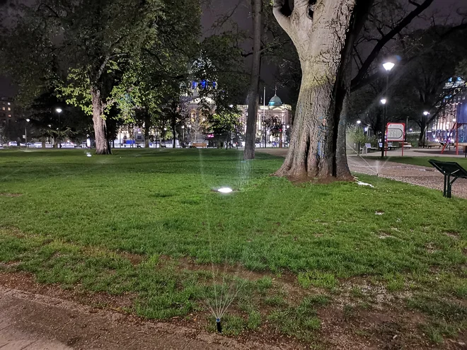 Kljub dežju so v Beogradu dolgo v noč zalivali celotni Pionirski park. Tako so verjetno preprečili, da bi si ljudje na razmočenem terenu pred skupščino postavili šotore. FOTO: Milena Zupanič/Delo