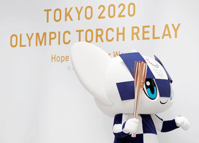 Maskota Miraitova izhaja iz besed Mirai (prihodnost) in Tova (večnost), na fotografiji pozira z olimpijsko baklo. FOTO: Reuters