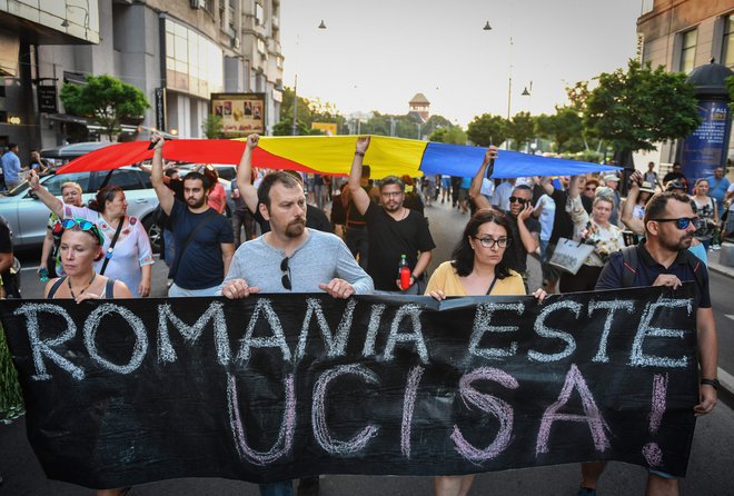 Demostranti s plakatom Romunija je ubita na sobotnih protesti v Bukarešti. FOTO: Daniel Mihailescu/AFP
