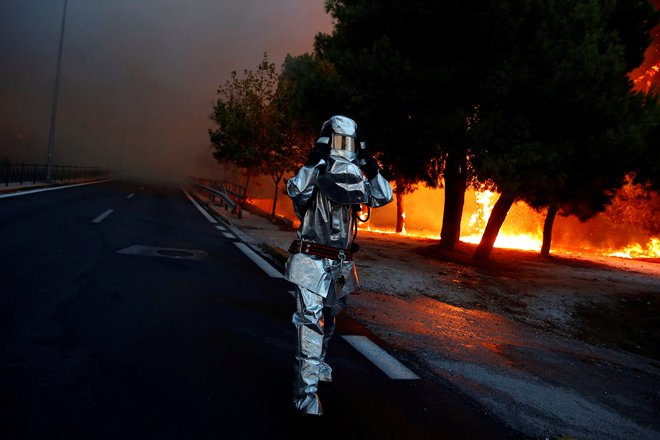 Na fotografiji gasilec v ognjevarni obleki julija lani gasi požar v mesti Rafina, v neposredni okolici grške prestolnice. FOTO: Costas Baltas/Reuters