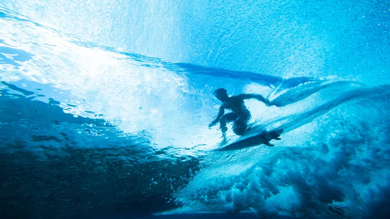 Fotografija: Pogled iz morske gladine na deskarja ki surfa na vodni gladini ob obali polinezijskega otoka Tahiti. FOTO: Brian Bielmann/AFP