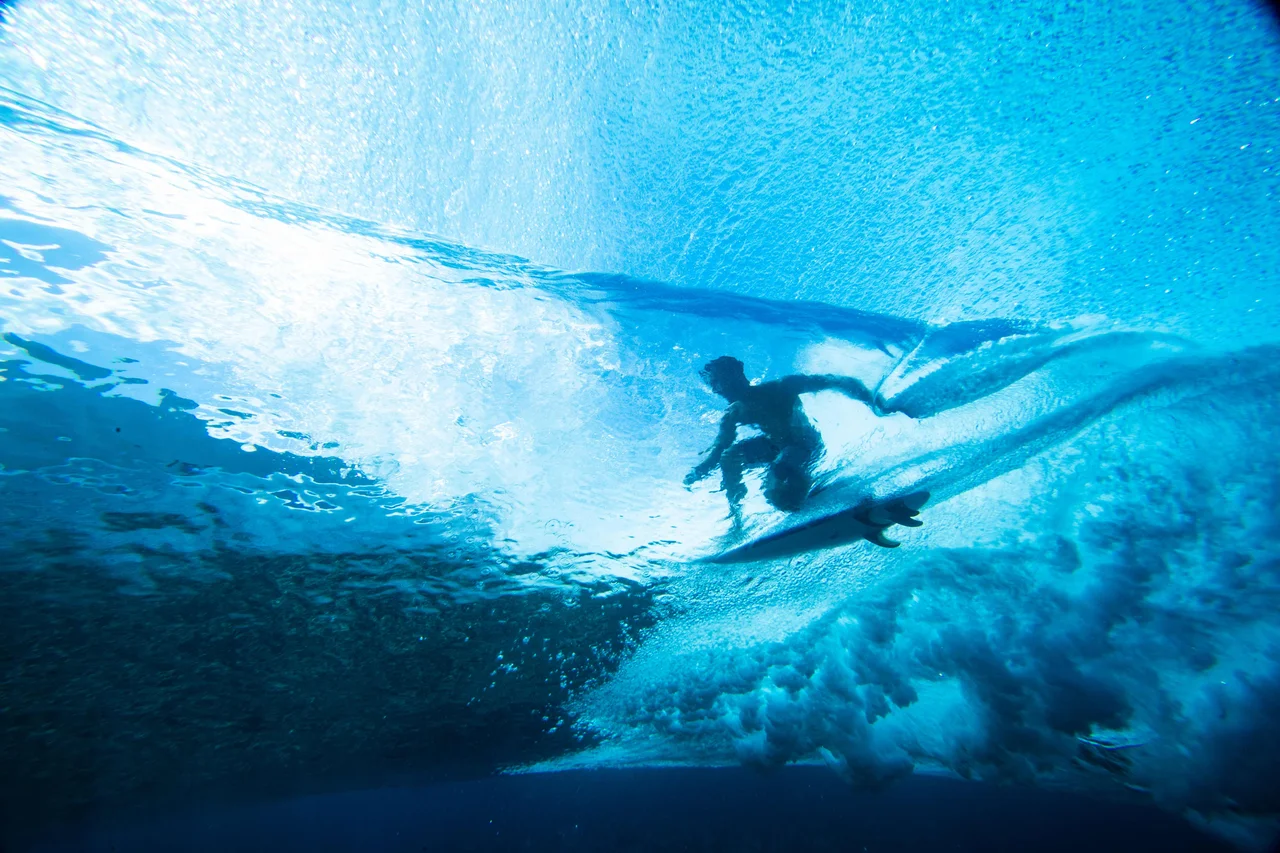 Fotografija: Pogled iz morske gladine na deskarja ki surfa na vodni gladini ob obali polinezijskega otoka Tahiti. FOTO: Brian Bielmann/AFP