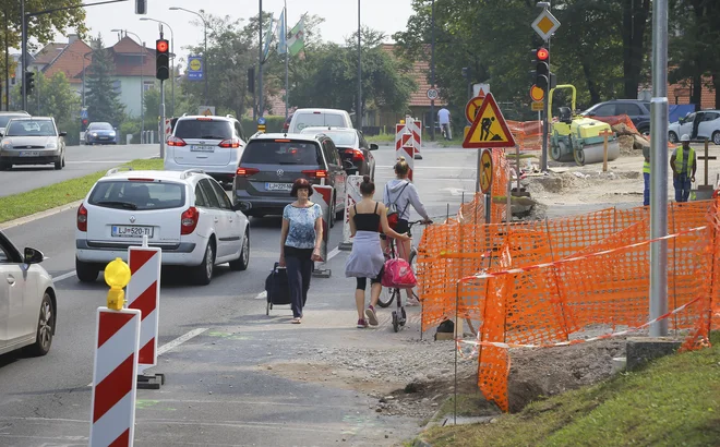 Z Drenikove bo po obnovi na Parmovo mogoče zaviti po posebnem pasu. Za zdaj pa se pešci in kolesarji po nasuti klančini prebijajo kljub prepovedi. FOTO: Jože Suhadolnik/Delo