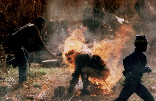 V spopadih med privrženci političnih strank Afriški nacionalni kongres (ANC) in Inkatha je v Južni Afriki leta 1990 umrlo več kot tri tisoč ljudi. Na fotografiji je pripadnik ANC z mačeto napadel gorečega pripadnika Inkathe. Greg Marinovich je za to fotografijo leta 1991 prejel Pulitzerjevo nagrado. FOTO: Greg Marinovich