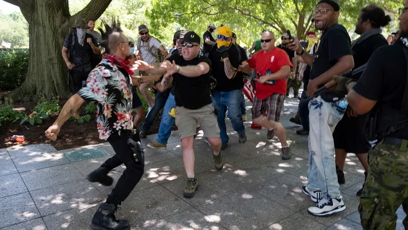 Fotografija: Član gibanja Boogaloo, ki nosi havajsko srajco, se je med protestom podpornikov desnice Proud boys spustil v fizični obračun v Columbusu, v zvezni državi Ohio. Protestniki so organizirali shod proti nošenju mask kot odgovor na lokalne zakone, ki zahtevajo obvezno nošenje mask v Ohiu. FOTO: Jeff Dean/Afp