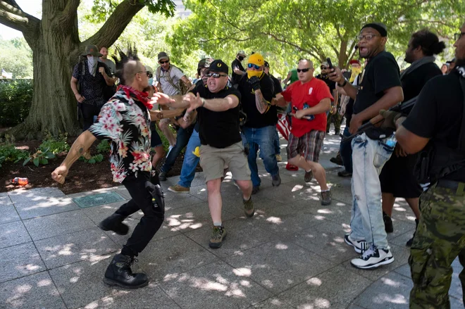 Član gibanja Boogaloo, ki nosi havajsko srajco, se je med protestom podpornikov desnice Proud boys spustil v fizični obračun v Columbusu, v zvezni državi Ohio. Protestniki so organizirali shod proti nošenju mask kot odgovor na lokalne zakone, ki zahtevajo obvezno nošenje mask v Ohiu. FOTO: Jeff Dean/Afp