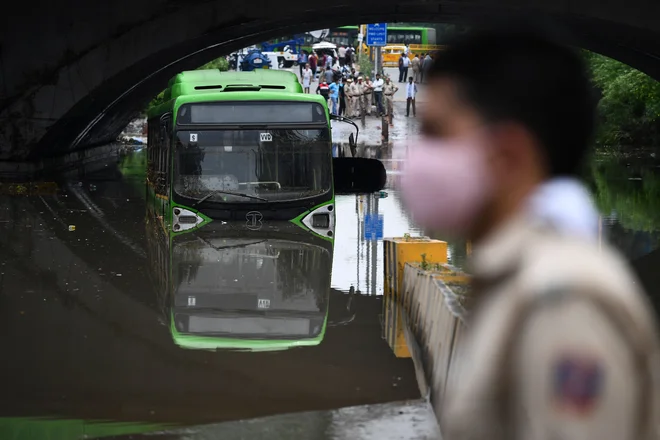 Policist ob reki Minto v New Delhiju po močnem jutranjem deževju. FOTO: Sajjad Hussain/AFP