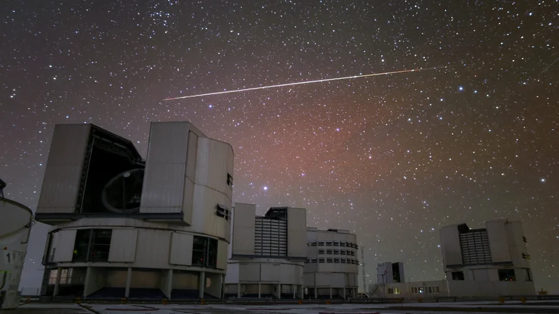 Fotografija: Sateliti so že doslej motili opazovanja, a jih ni bilo toliko, da se astronomi ne bi mogli prilagoditi. Svetla sled umetnega satelita je bila posneta nad Zelo velikim teleskopom observatorija Paranal v čilski puščavi Atakama. FOTO: Roger Wesson/Eso