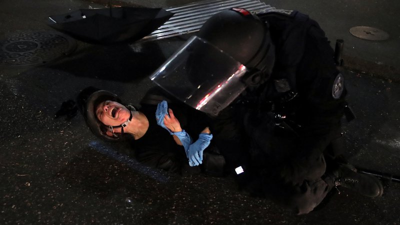 Fotografija: Protestnica Dana Parks reagira, ko jo je v Portlandu policist med protestom proti rasni neenakosti in nasilju v policiji z uporabo sile aretiral. FOTO: Caitlin Ochs/Reuters
 