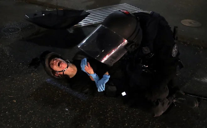 Protestnica Dana Parks reagira, ko jo je v Portlandu policist med protestom proti rasni neenakosti in nasilju v policiji z uporabo sile aretiral. FOTO: Caitlin Ochs/Reuters<br />
