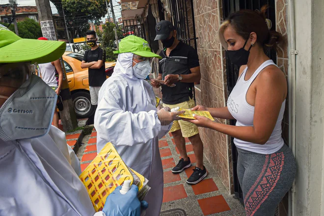 V kolumbijskem Medellinu ljudi motivirajo, da ostajanje doma, z igro Bingo. Na fotografiji razdeljevanje kartic. FOTO: Joaquin Sarmiento/AFP