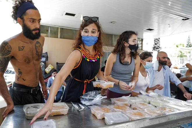 Prostovoljci v Bejrutu med razdeljevanjem hrane ljudem, ki so bili prizadeti v uničujoči eksploziji. FOTO: Anwar Amro/AFP