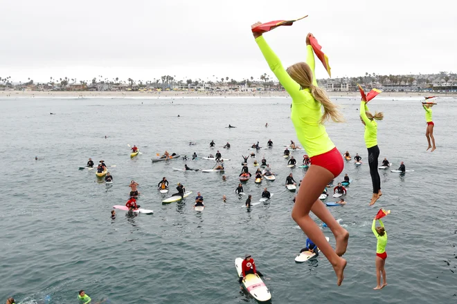 Mladi udeleženci programa za reševalce iz vode (San Diego Junior Lifeguard) skačejo s pomola na letnem obredu v Ocean Beachu v Kaliforniji. FOTO: Mike Blake/Reuters