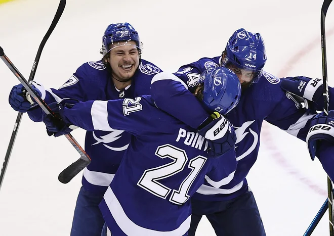 Brayden Point se je takole s soigralci pri moštvu Tampa Bay Lightning veselil zmagovitega gola po debelih šestih urah tekme s tekmeci iz Columbusa. FOTO: AFP
