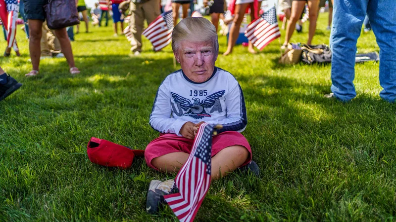 Fotografija: V mestu Mankato v ameriški zvezni državi Minnesota, kjer poteka shod podpornikov Trumpa, deček nosi masko ameriškega predsednika. FOTO: Kerem Yucel/Afp