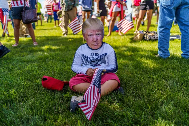 V mestu Mankato v ameriški zvezni državi Minnesota, kjer poteka shod podpornikov Trumpa, deček nosi masko ameriškega predsednika. FOTO: Kerem Yucel/Afp