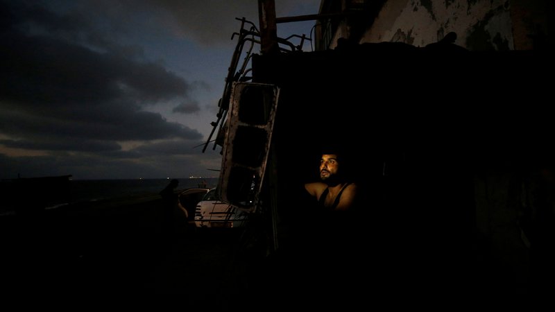 Fotografija: Palestinec ima pritrjeno baterijsko lučko v svoji trgovini med izklopom električne energije. Edina elektrarna v Gazi je zaradi vse večjih napetost z Izraelom preventivno nehala obratovati. Napetosti nastajajo zaradi pomanjkanja goriva v palestinski enklavi, ki jo je povzročila izraelska blokada. FOTO:Mohammed Salem/Reuters