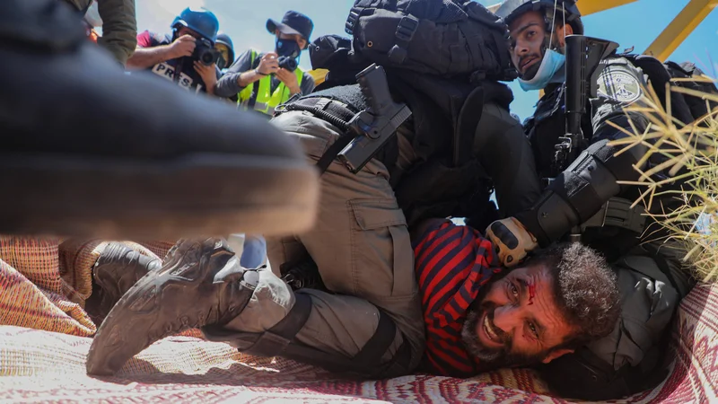 Fotografija: Izraelski vojak med aretacijo Palestinca blizu vasi Shoufah na okupiranem Zahodnem bregu, ki protestira proti čiščenju zemljišč za širitev izraelskih naselij. FOTO: Jaafar Ashtiyeh/Afp