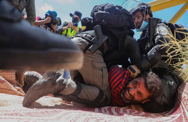 Izraelski vojak med aretacijo Palestinca blizu vasi Shoufah na okupiranem Zahodnem bregu, ki protestira proti čiščenju zemljišč za širitev izraelskih naselij. FOTO: Jaafar Ashtiyeh/Afp