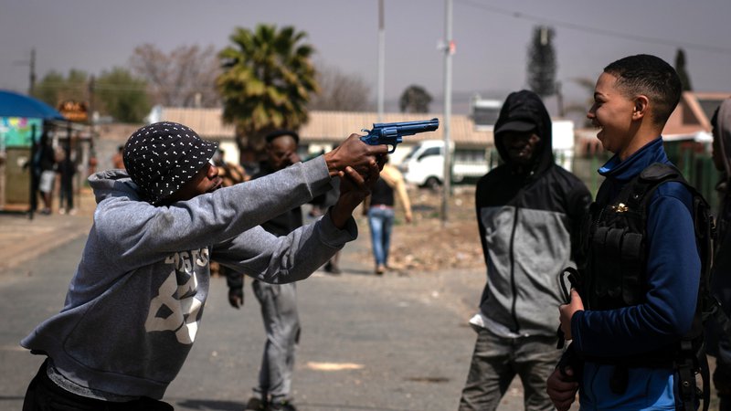Fotografija: Med protesti članov skupnosti v parku Eldorado v Johannesburgu, zaradi smrti šestnajstletnega dečka, ki ga je ubil policaj, njegovi prijatelji uprizarjajo tragični dogodek z repliko strelnega orožja. FOTO: Ali Greef/Afp