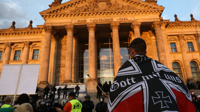 Fotografija: Nemški »Bog z nami« na zastavi. Protesta so se udeležile različne skupine, nekateri so na policiste metali kamenje in steklenice, za kar so oblasti okrivile desničarske skrajneže. FOTO: Christian Mang/Reuters