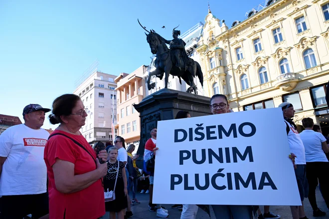 Protestnica s transparentom "Dihamo s polnimi pljuči" na protestu v Zagrebu. FOTO: Denis Lovrovic/AFP