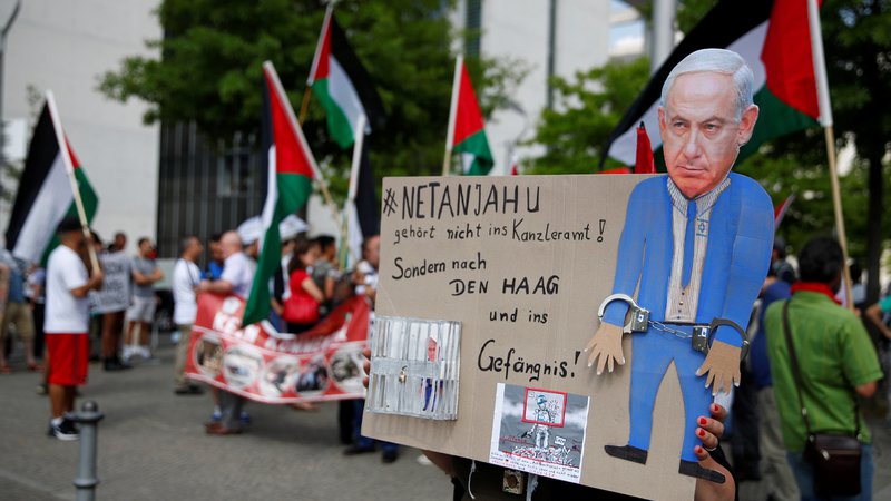Fotografija: Netanjahu bi moral biti v Haagu, ne pa v »Kanzleramtu«, piše na plakatu pred sedežem nemške vlade. Foto Reuters