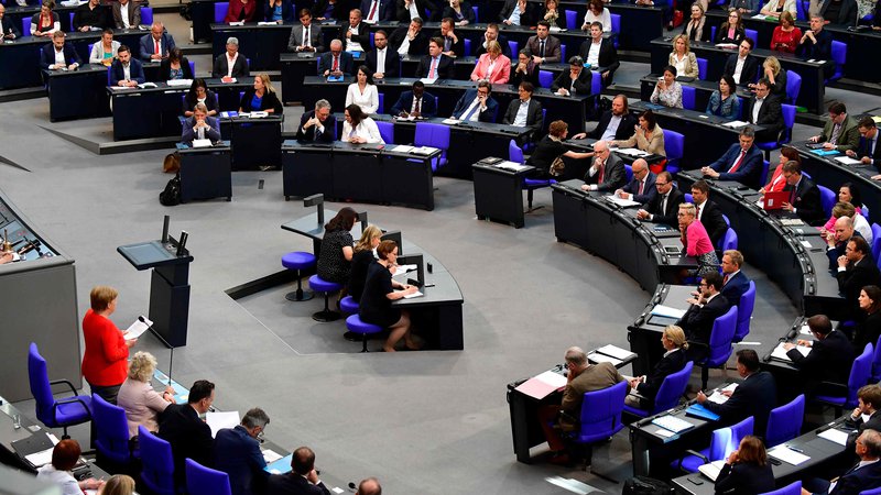 Fotografija: Kanclerka Angela Merkel (levo spodaj v rdečem suknjiču) med odgovarjanjem na vprašanja poslancev v bundestagu. FOTO: AFP