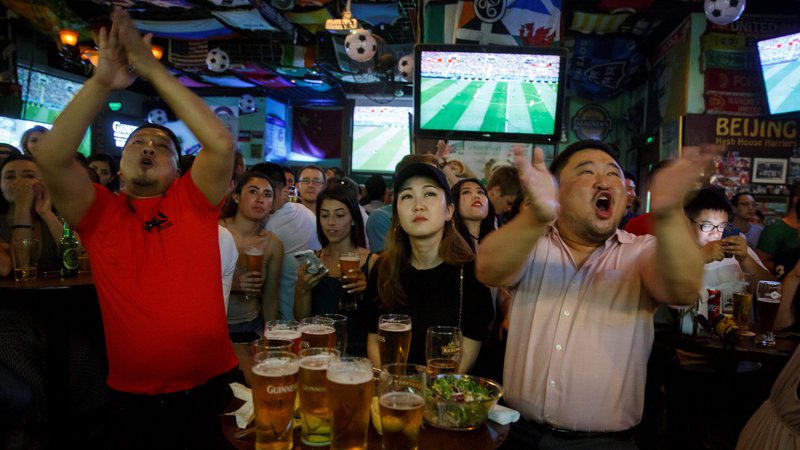 Fotografija: Kitajski ljubitelji nogometa med ogledom uvodne tekme SP med Rusijo in Savdsko Arabijo v enem od pekinških barov. FOTO: Reuters