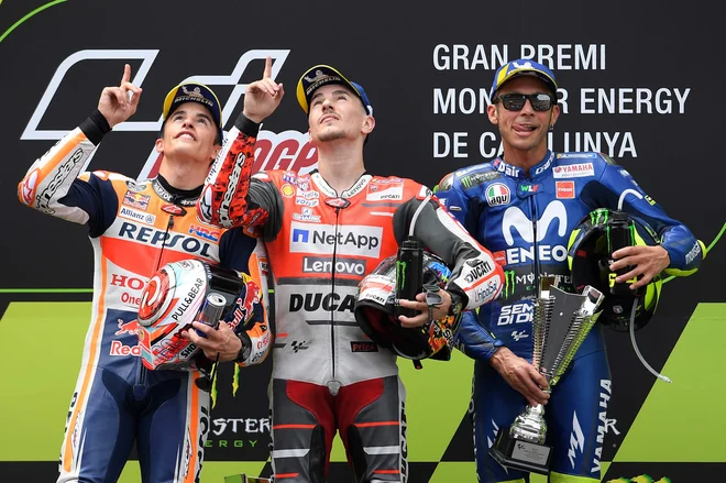 Španca Jorge Lorenzo (na sredini) in Marc Marquez (levo) sta se takole na zmagovalnem odru spomnila pred tednom dni tragično preminulega komaj 14-letnega rojaka Andreasa Pereza. Italijanski veteran Valentino Rossi (desno) je bil zadovoljen s tretjim mestom.<br />
FOTO: AFP
