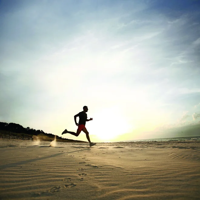 Man running on beach at sunset