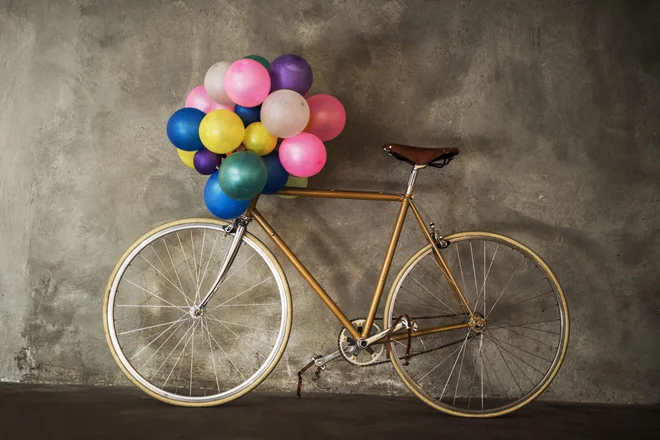 Old-fashioned bicycle leaned on the wall with colorful balloons.
